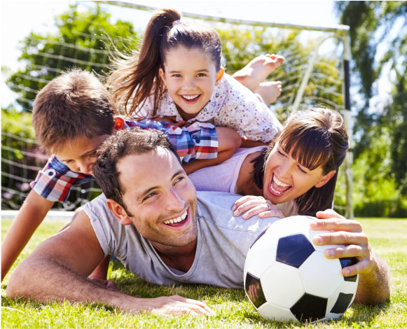 Family of a mom, dad, and 2 kids playing soccer together.