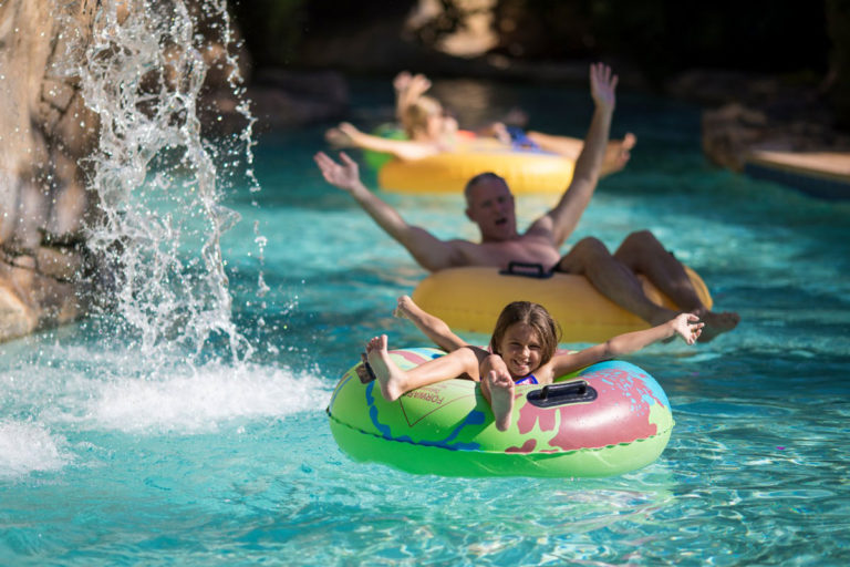 Niña y familia montando en el río perezoso en el parque acuático de Spectrum Resort Orlando.