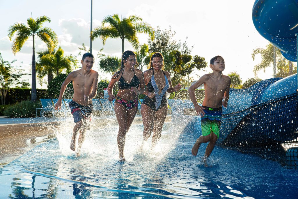 Kids And Teens Jogging And Splashing Through The Water Park.