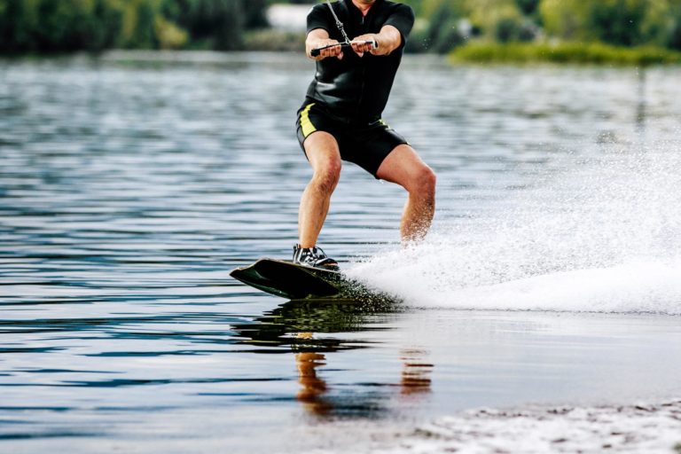 Extreme sports man rides a wakeboard on lake