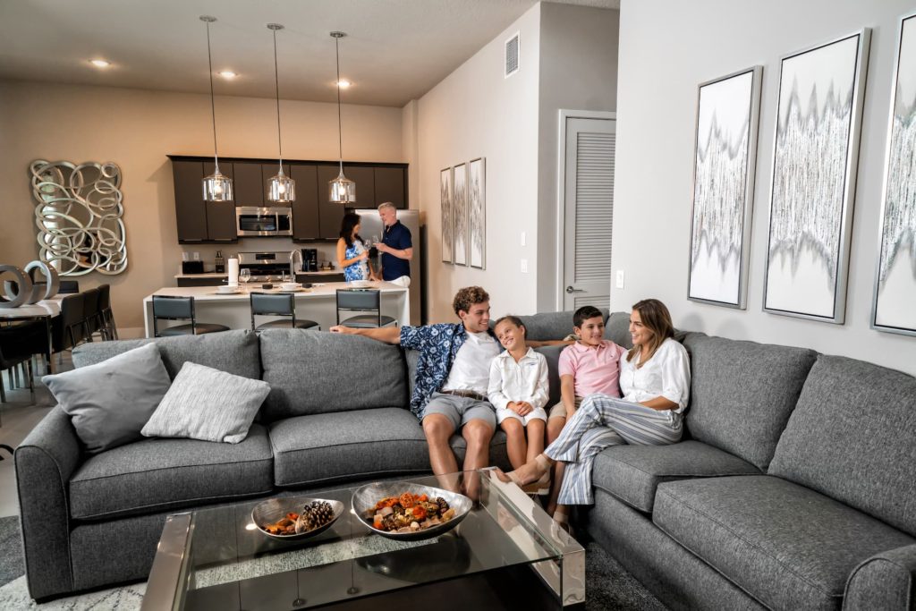 Family sitting together on a large sectional sofa in a Spectrum Resort Orlando living room