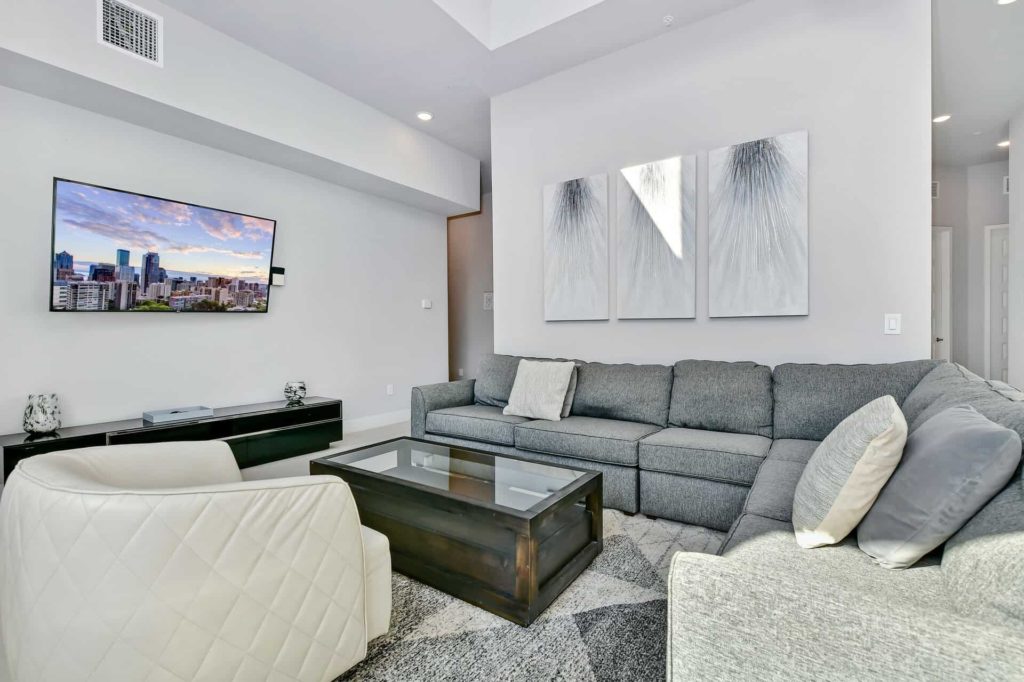 Living room with sectional sofa, armchairs, and wall-mounted TV: 5 Bedroom Condo
