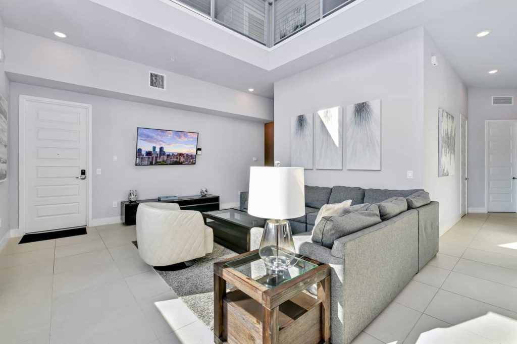 Living room with sectional sofa, end table, and wall-mounted TV: 5 Bedroom Condo