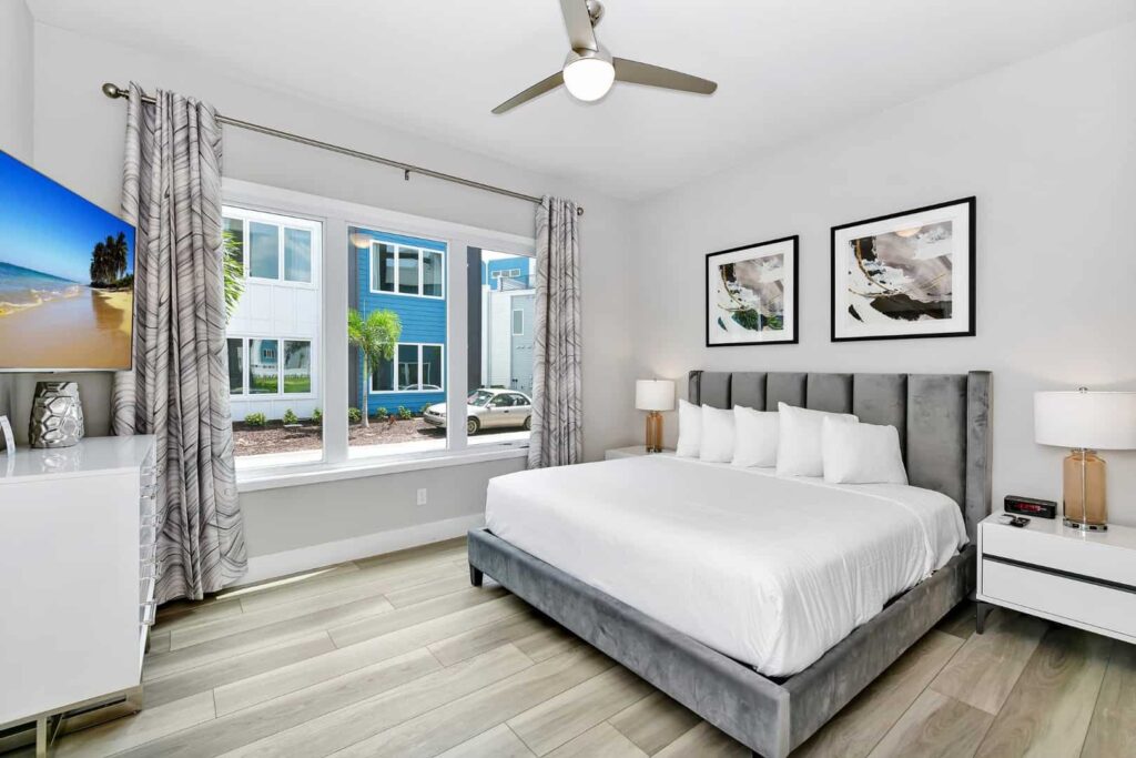 Dormitorio 2 con cama King, mesitas de noche gemelas, tocador y televisor montado en la pared