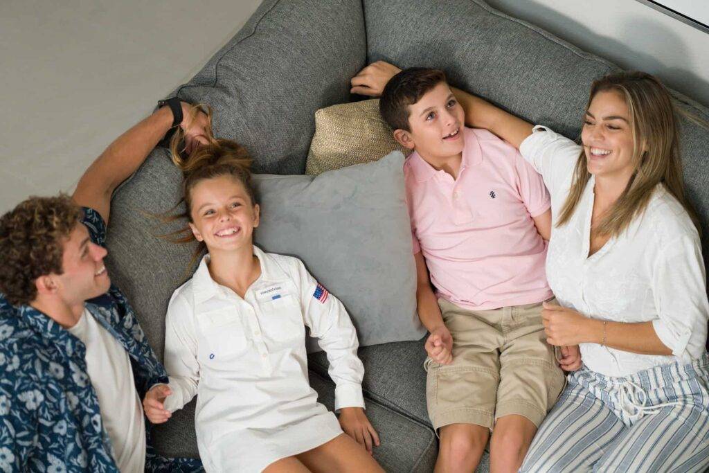 Family of a mother, father, and two young kids sitting together on a couch in a Spectrum Resort Orlando condo