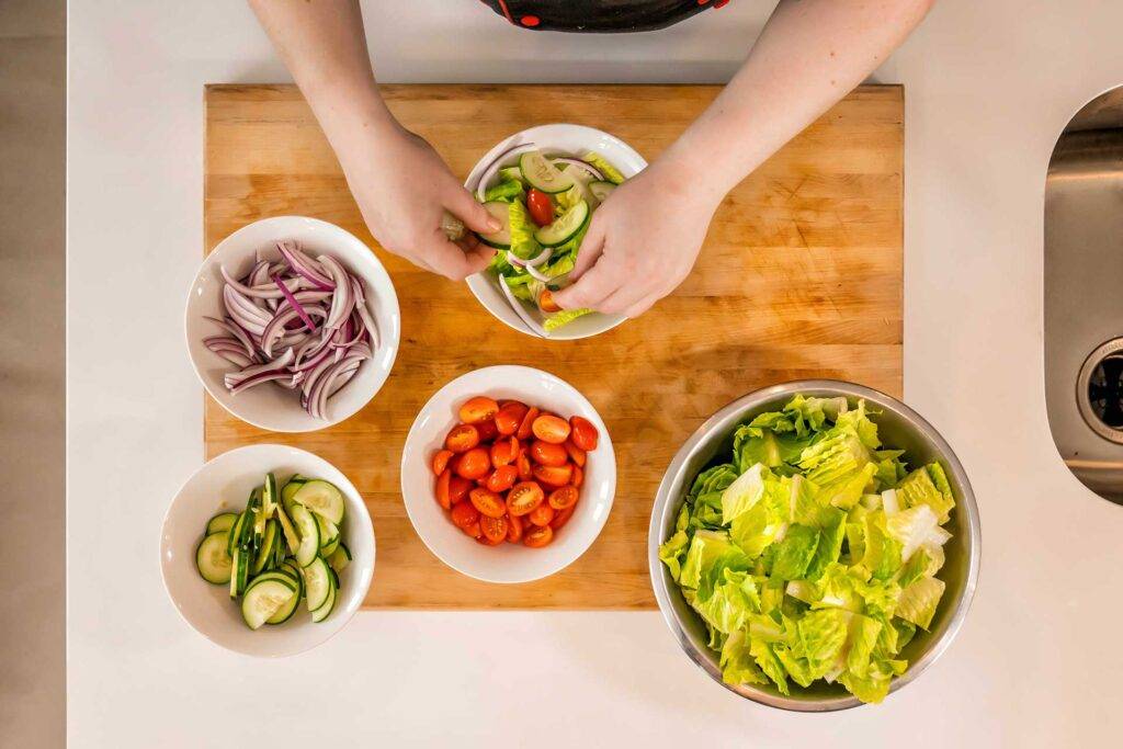 Bowls of prepared salad ingredients on a kitchen counter