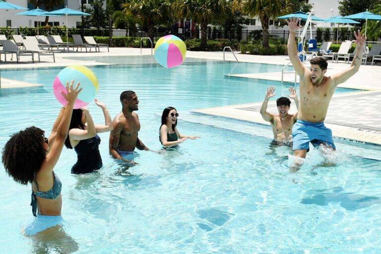 Grupo de amigos jugando con pelotas de playa en el Spectrum Resort clubhouse alberca