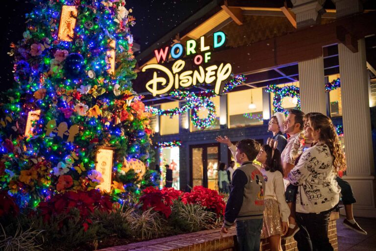 Familia admirando el árbol de Navidad frente a la tienda World of Disney en Disney Springs