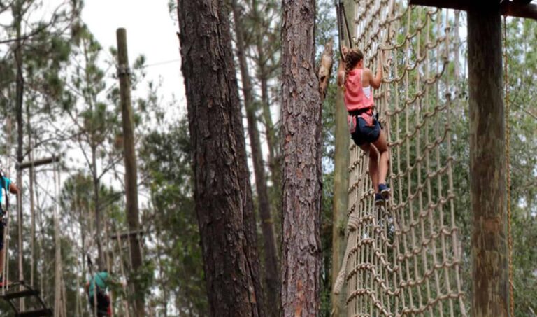 Mujer trepando una red de cuerdas en Orlando Tree Trek Adventure