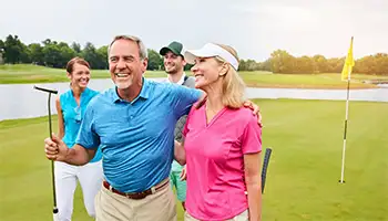 Golf Group Getaways: Happy, mature couple with friends walking on a golf course