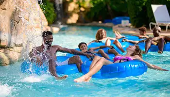 Stay More, Save More: Happy family in tubes in the water park lazy river