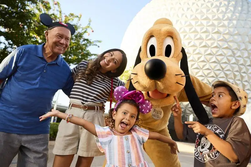 Happy family posing for a photo with Pluto in front of Spaceship Earth at EPCOT